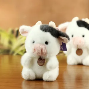 Cute plush cow stuffed animal toy with black and white spots and wooden tag detail.