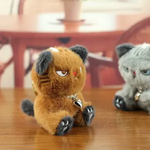 Süßer Plüsch Katzen Schlüsselanhänger Detail mit gestickten Augen und Glocke Holztisch.