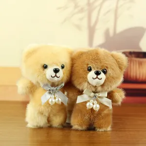 Close-up detail of cute fluffy teddy bear plush pendant with elegant bow and pearl charm.