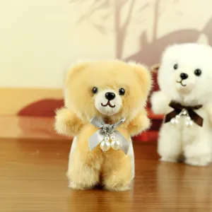 Detailed shot of cute plush bear bag pendant with pearl bow, fluffy stuffed animal toy.