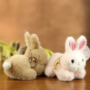 Close up detail of cute plush rabbit keychains with soft faux fur and gold keyring pendants.