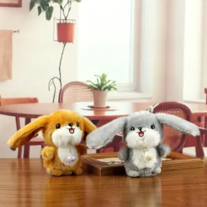 Close-up detail shot of cute plush bunny keychains with big ears, necklaces, and soft toy dolls.