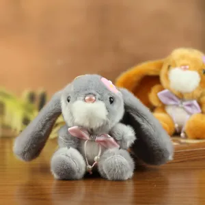 Detalle de muñeco de peluche de conejo, suave conejito gris colgante con lazo y perla.