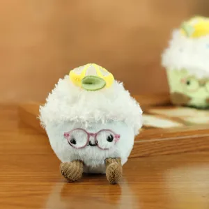 Primo piano di un simpatico peluche a torta con occhiali rosa e morbide zampette.