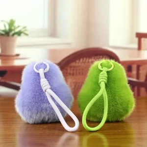 Nahaufnahme von flauschigen Avocado Plüsch-Schlüsselanhängern in Lila und Grün auf Tisch.