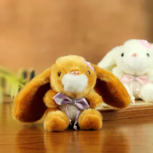 Lindo conejito de peluche marron muneca colgante con lazo morado primer plano detalle