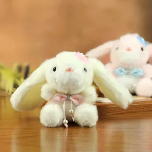 Vista detallada de lindo peluche de conejo con orejas largas, lazo rosado y colgante de perla.