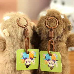 Close-up detail van schattige bruine pluche otter sleutelhanger met groene cartoon hanger.