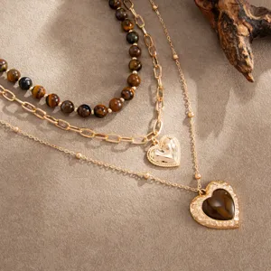 Detailopname van de vintage gelaagde ketting met tijgeroog kralen en gegraveerde hart hangers.