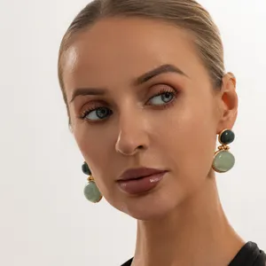 Nahaufnahme von eleganten retro-goldenen Ohrringen mit grünen Steinen von Model getragen.