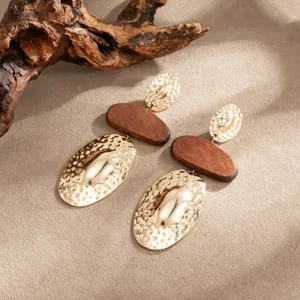 Nahaufnahme von detailreichen geometrischen Holz und Hammerschlag Gold Ohrringen.