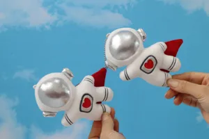 Nahaufnahme niedlicher Astronaut Plüsch Anhänger mit Silberhelm und rotem Umhang Detail.