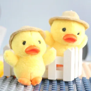 Primo piano dettaglio di ciondolo paperella peluche giallo con piccolo cappello di paglia dolce.