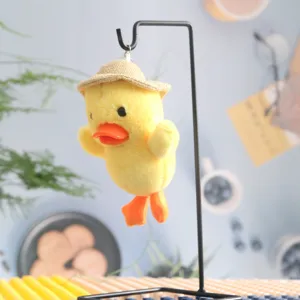 Dettaglio di un grazioso ciondolo in peluche di anatra gialla con un mini cappello di paglia.
