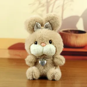 Détail en gros plan du pendentif lapin en peluche marron avec nœud brillant et collier cœur.