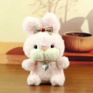 Gros plan détaillé d'une jolie poupée lapin en peluche avec nœud coloré et pendentif cœur.