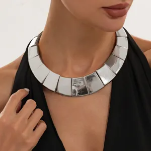 Detalle de gargantilla de metal plateado grueso, diseño de bloque moderno para look de moda.