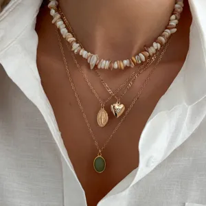 Collier superposé avec ras de cou coquillage coloré, chaînes dorées, médaillon cœur et pendentif vert.