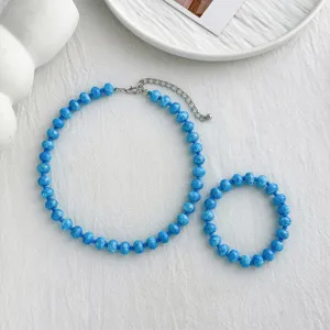 Nahaufnahme Detail des blauen Perlenketten und Armband Sets mit Metallverschluss auf Stoff.