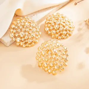 Detailed close-up of luxury gold-plated irregular openwork geometric stud earrings or rings.