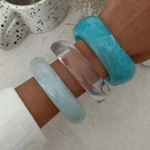 Set di bracciali rigidi in resina spessa con design blu, trasparenti e marmorizzati per look.