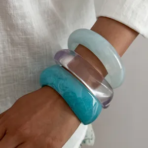 Primo piano dettaglio di bracciali rigidi in resina spessa, bei bracciali impilabili.