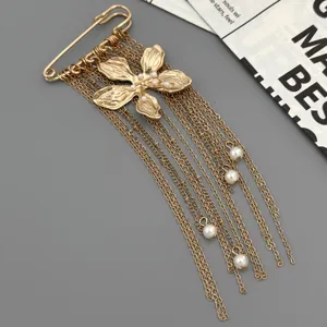 Exquisite gold safety pin brooch with floral charm and delicate tassel chains for women.