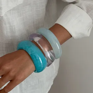 Primo piano dettagliato del set di bracciali in resina blu marmorizzata, stile chic minimalista.