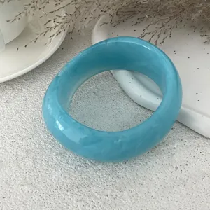 Vista dettagliata del bracciale rigido in resina blu con superficie lucida e venatura.