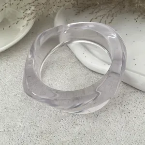 Dettaglio bracciale rigido geometrico in resina trasparente, stile minimalista moderno.