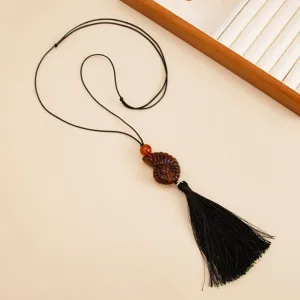 Long resin conch pendant necklace with adjustable wax rope and tassel for women detail view.
