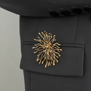 Gold irregular branch flower brooch detail on dark grey blazer fabric. Elegant party jewelry.