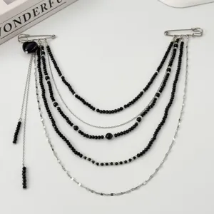 Detailed close-up of multi-strand black bead clothing chain brooch with dual safety pins design.