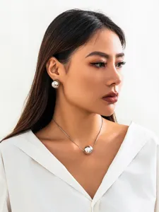 Close-up of minimalist silver snake bone chain necklace and matching ball earrings set.