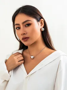 Detail view of minimalist silver snake bone chain necklace with a geometric round ball pendant.