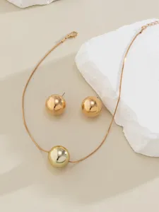 Detailed view of the golden snake bone chain necklace and matching round ball stud earrings.
