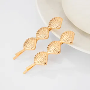 Gold metal shell hair clip detail shot, elegant beach style hair accessory for women.