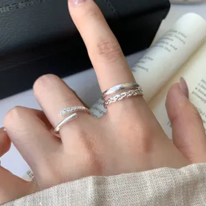 Close-up detail of stylish stackable silver open rings with sparkling zircon and matte texture.