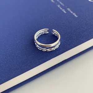 Silver open ring closeup showing double band design with smooth and braided texture details.