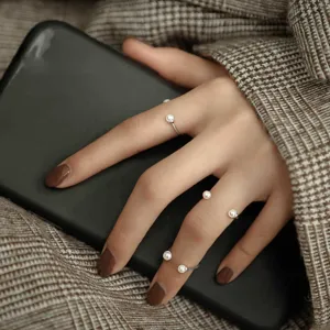 Close-up detail of stylish multi-layer open pearl rings worn on fingers with elegant look.