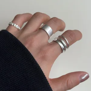 Detail shot of minimalist matte geometric silver rings, showcasing unique texture and layered design.