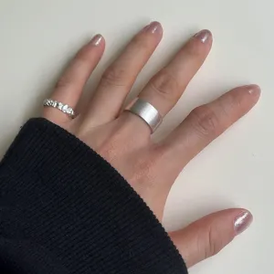 Minimalist silver rings set featuring a wide matte band and a textured minimalist design.