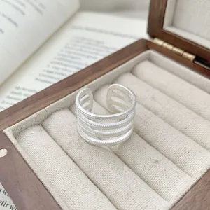 Detailed close-up of a stylish multi-layer silver open ring showcased inside a wooden box.