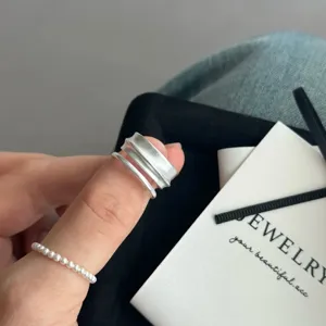 Gedetailleerde close-up van de minimalistische matgeborstelde geometrische ring en fijne parelring.