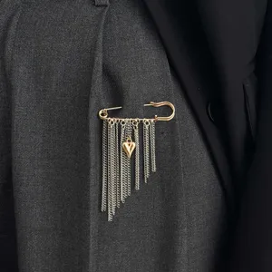 Close-up detail of elegant fashion safety pin brooch with hanging chains and sweet heart pendant.