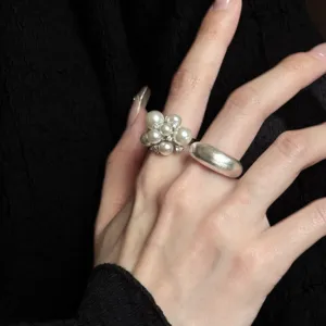 Close-up detail shot of stylish pearl cluster ring and silver band worn on hand.