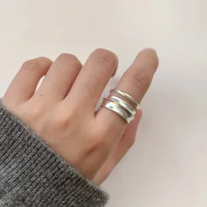 Gedetailleerde close-up van de stijlvolle matte zilveren meerlaagse geometrische ringen.