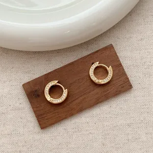 Detailed close-up view of dainty gold huggie hoop earrings with sparkling pavé cubic zirconia.