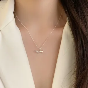 Gros plan détaillé d'un collier pendentif teckel argenté minimaliste sur modèle.