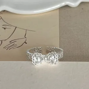 Silberner Offener Ring mit süßem Schleifendesign, Herzsteinen und filigranem Ajourmuster.